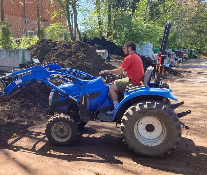 Man using tractor to scoop bulk mulch | bulk and bagged mulch supplies at The Dutch Plant Farm.