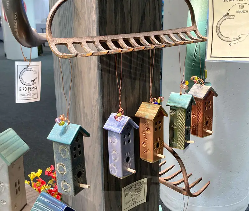 Ceramic birdhouses hanging from a rake are some of the bird supplies available at The Dutch Plant Farm store.