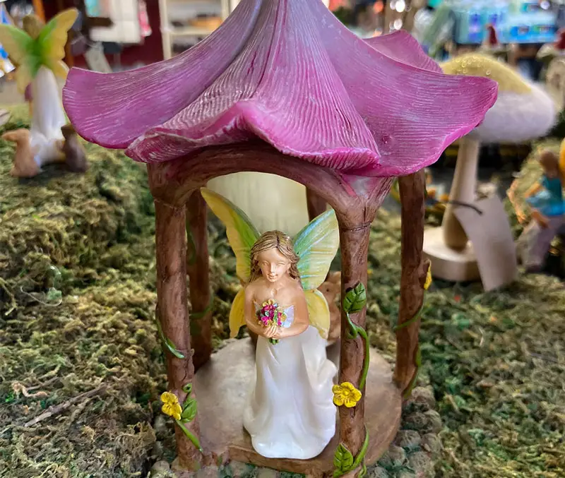 Fairy with wings in her pagoda house, is holding flowers and is one of the fun kids gardening supplies at The Dutch Plant Farm.