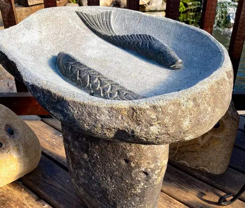 Stone birdbath with two fish carved in the basin are some of the bird supplies available at The Dutch Plant Farm store.